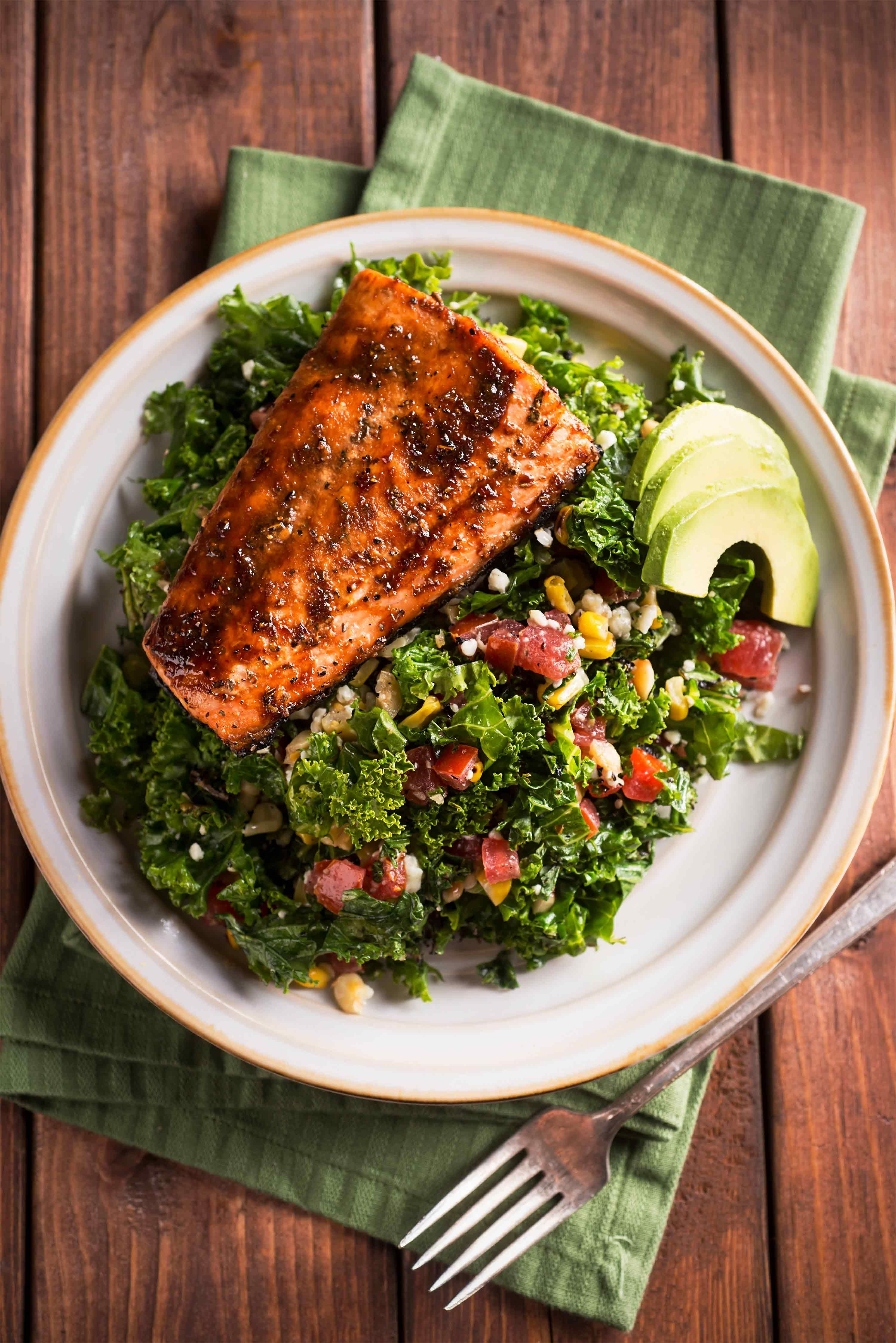 A plate of kale salad topped with grilled salmon.