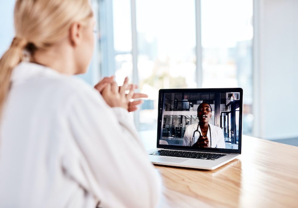 a photo of a doctor on a computer screen talking to a woman patient