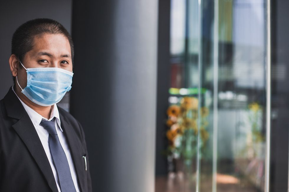 A business man wears a mask to limit the threat of coronavirus while at work.
