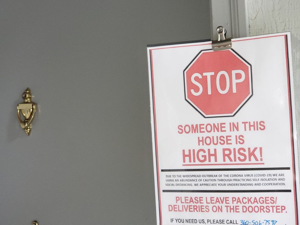 A sign posted at a door saying "STOP Someone in this house us HIGH RISK"