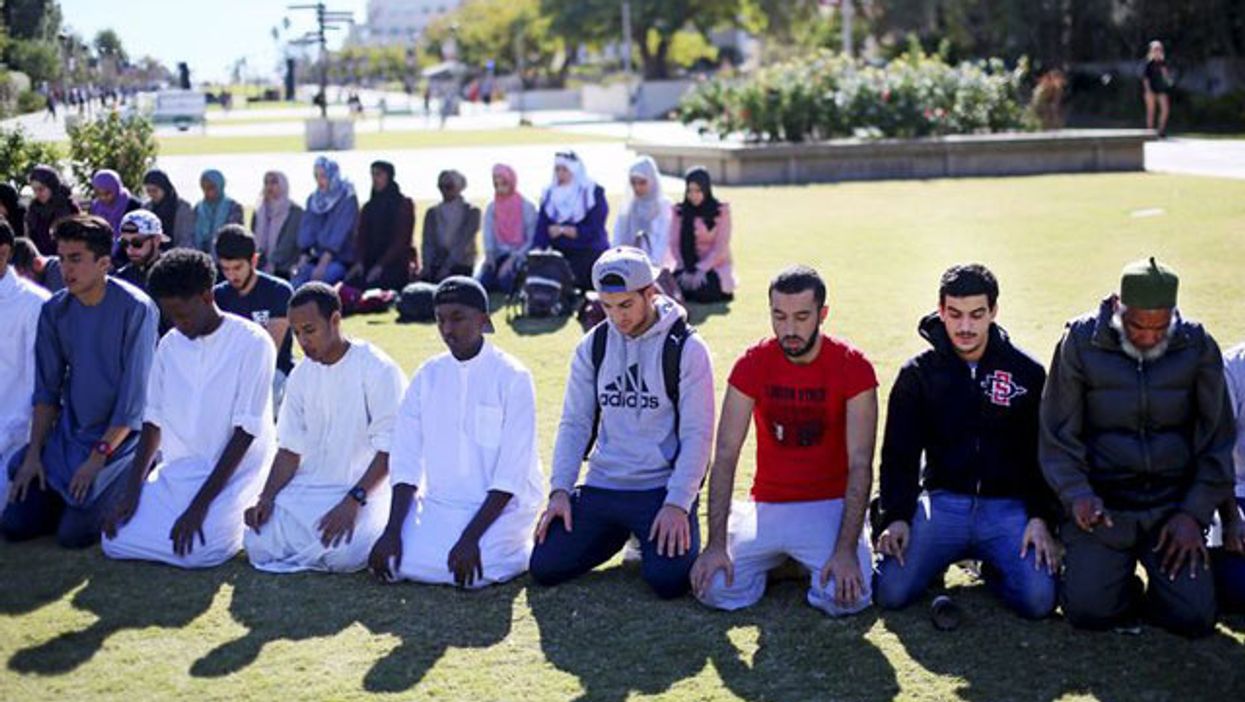 Muslim people praying in a park.