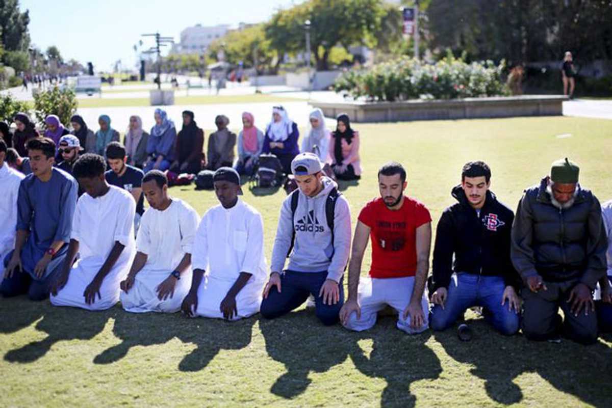 Muslim people praying in a park.