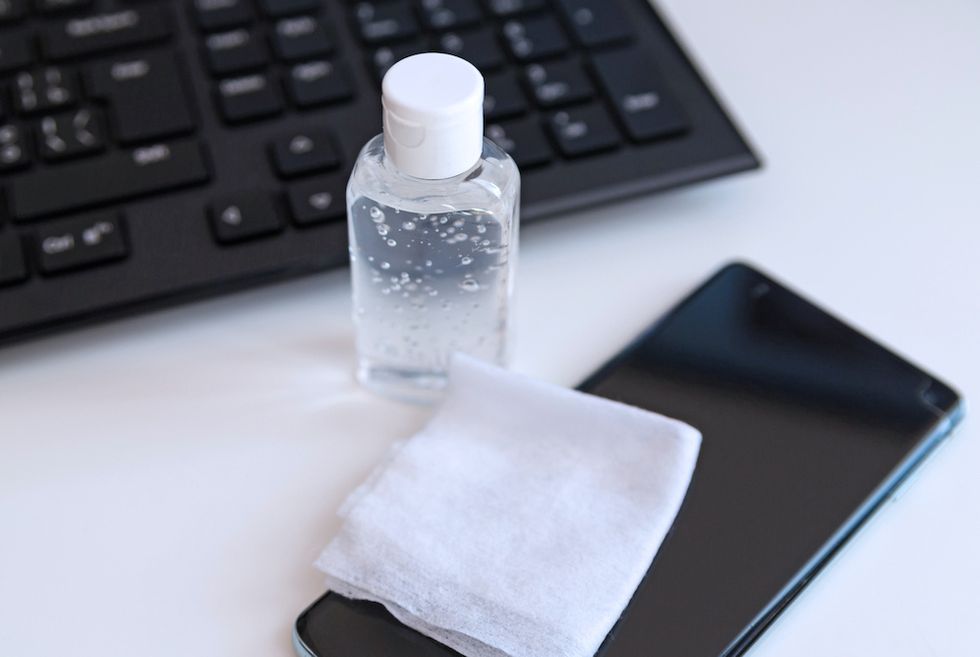 Cleaning workplace with computer, sanitizer gel, smartphone and napkin for cleaning the phone.