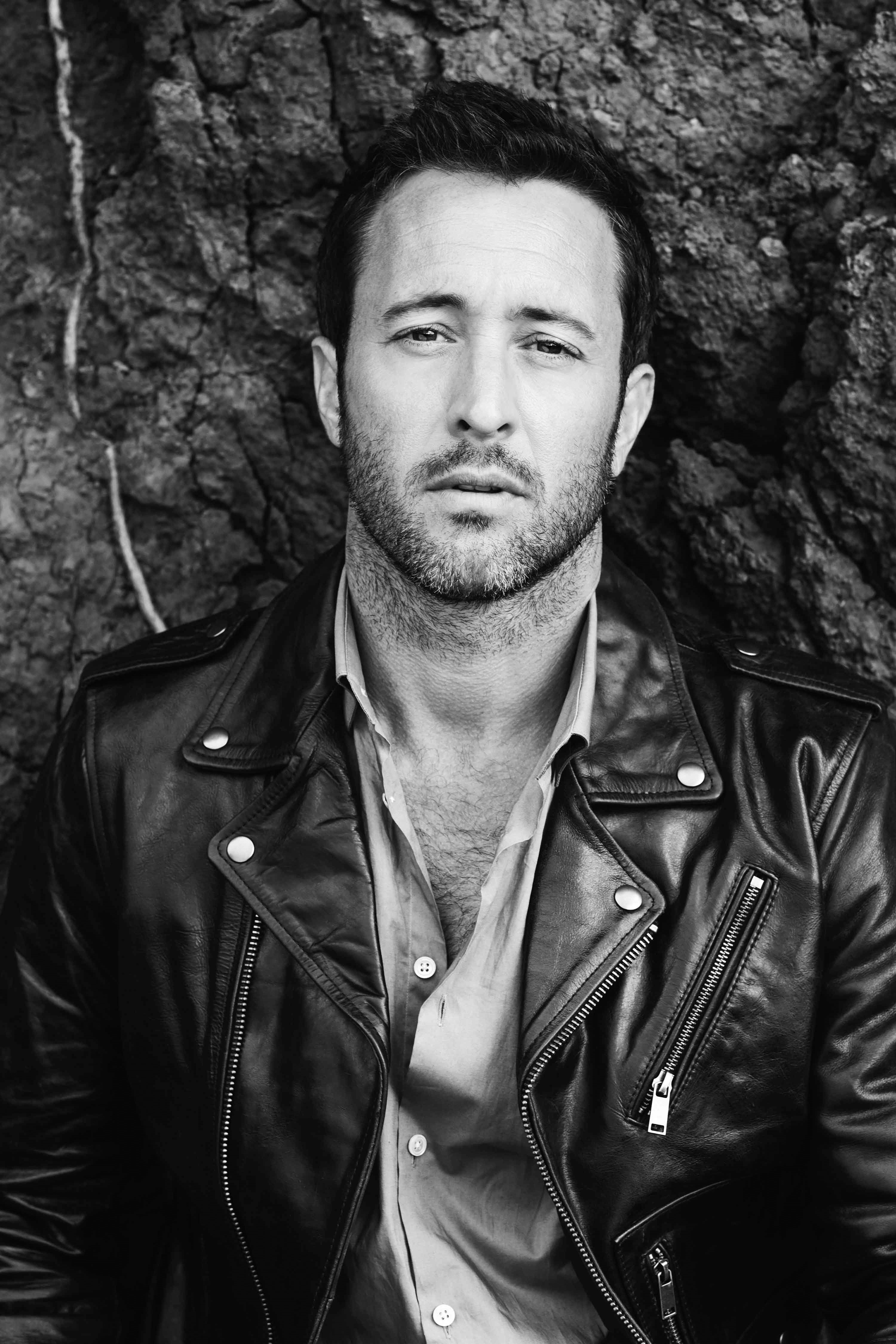 Black and white portrait of Alex O'Loughlin wearing a leather jacket.