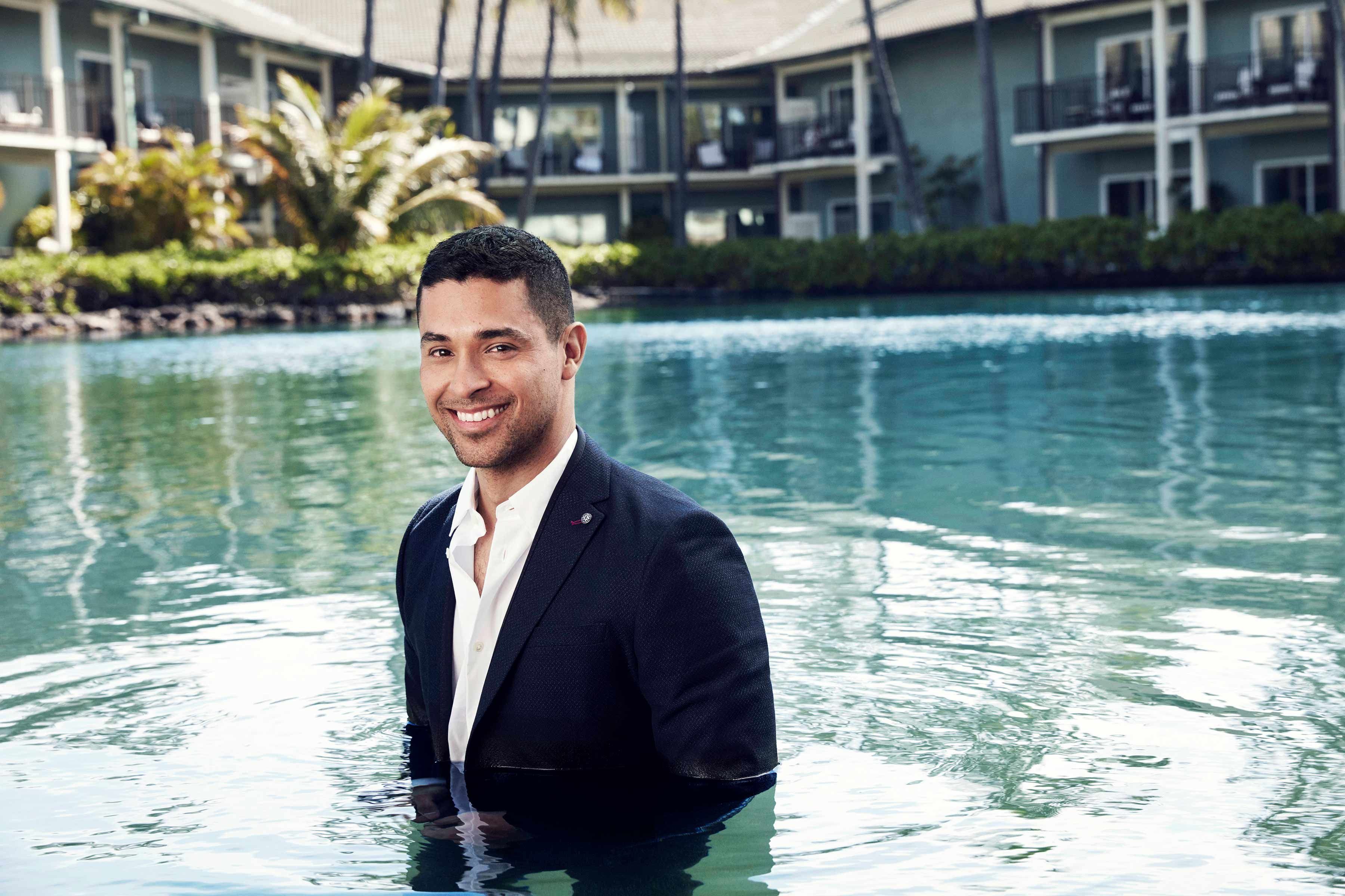 Wilmer Valderrama wearing a suit in a hotel pool