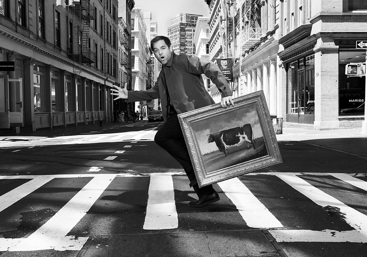 Michael Weatherly in a crosswalk holding a painting of a cow.