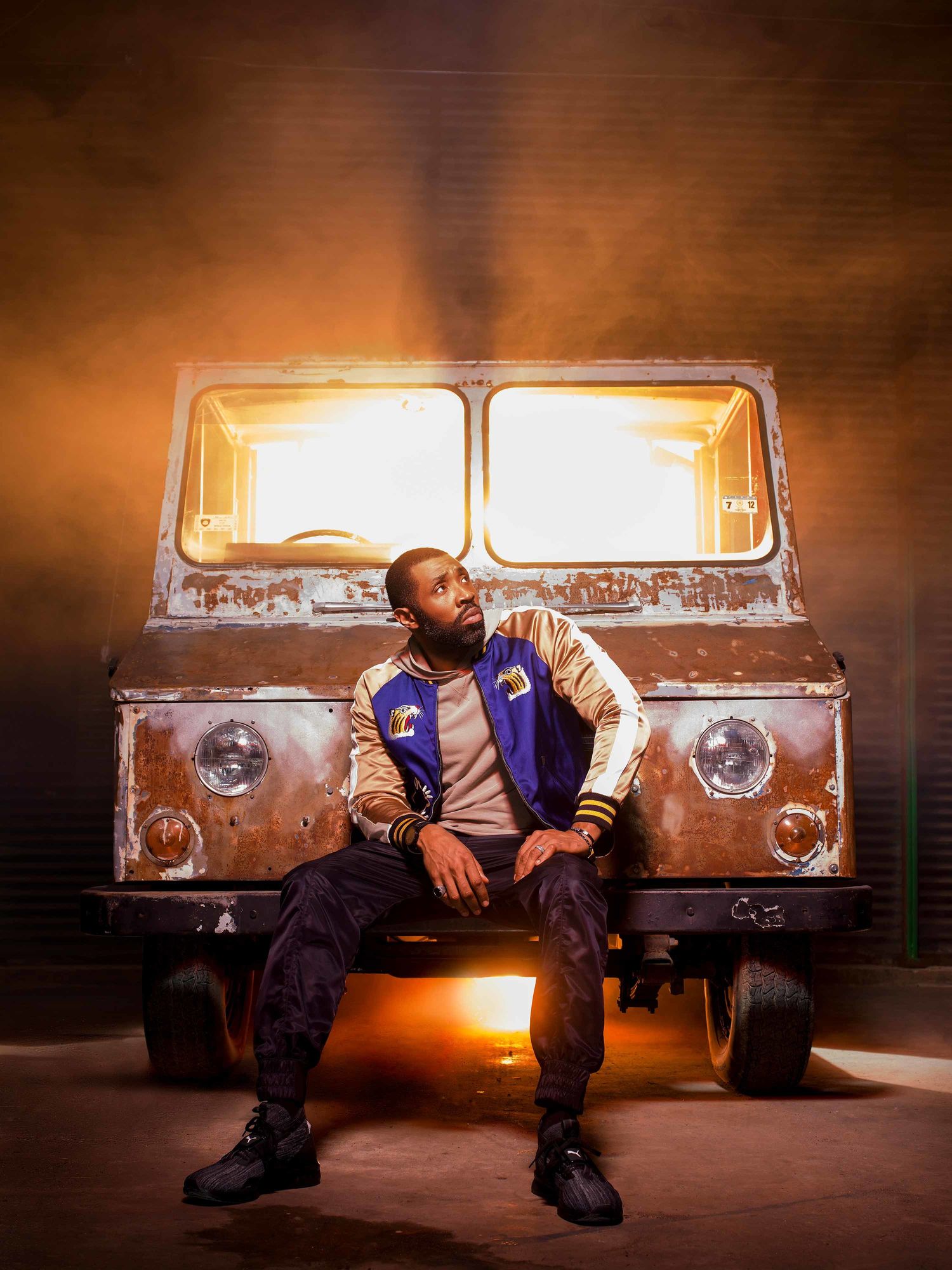 Cress Williams sitting on the front of a rusted truck.