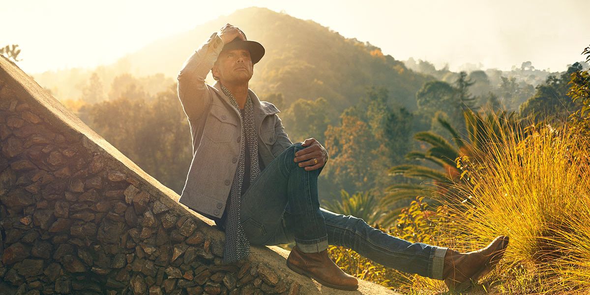 Walton Goggins sitting on a stone looking up to the sky.