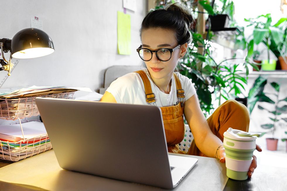Young professional works on her LinkedIn profile from her home office.