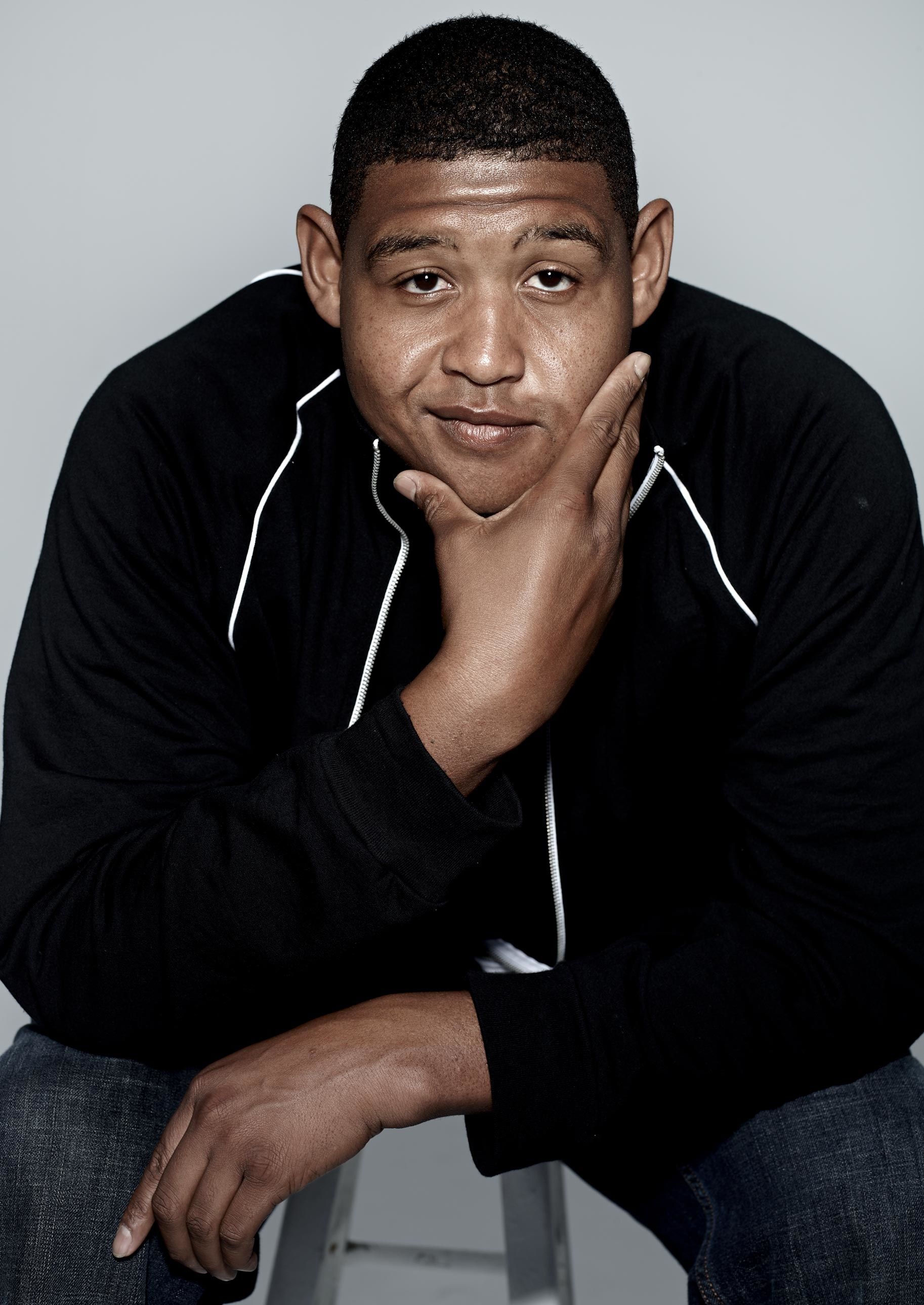 Actor Omar Miller sitting on a stool.