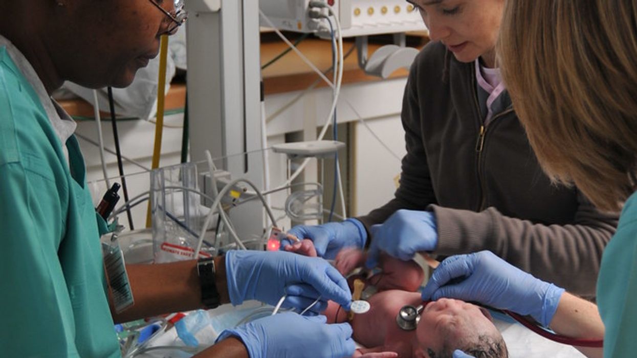 Medical officers helping a premature baby in a neonatal intensive care unit.