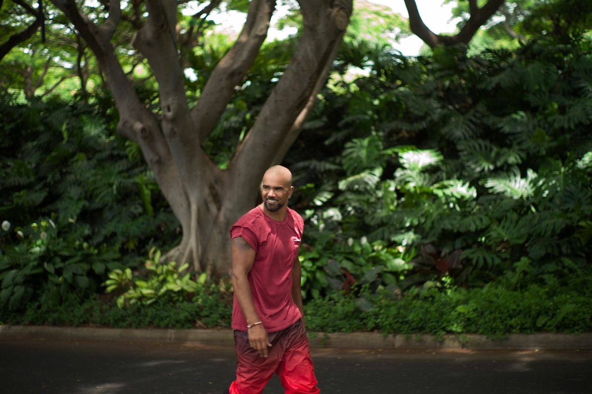 Shemar Moore walking outside in a red tank top and pants
