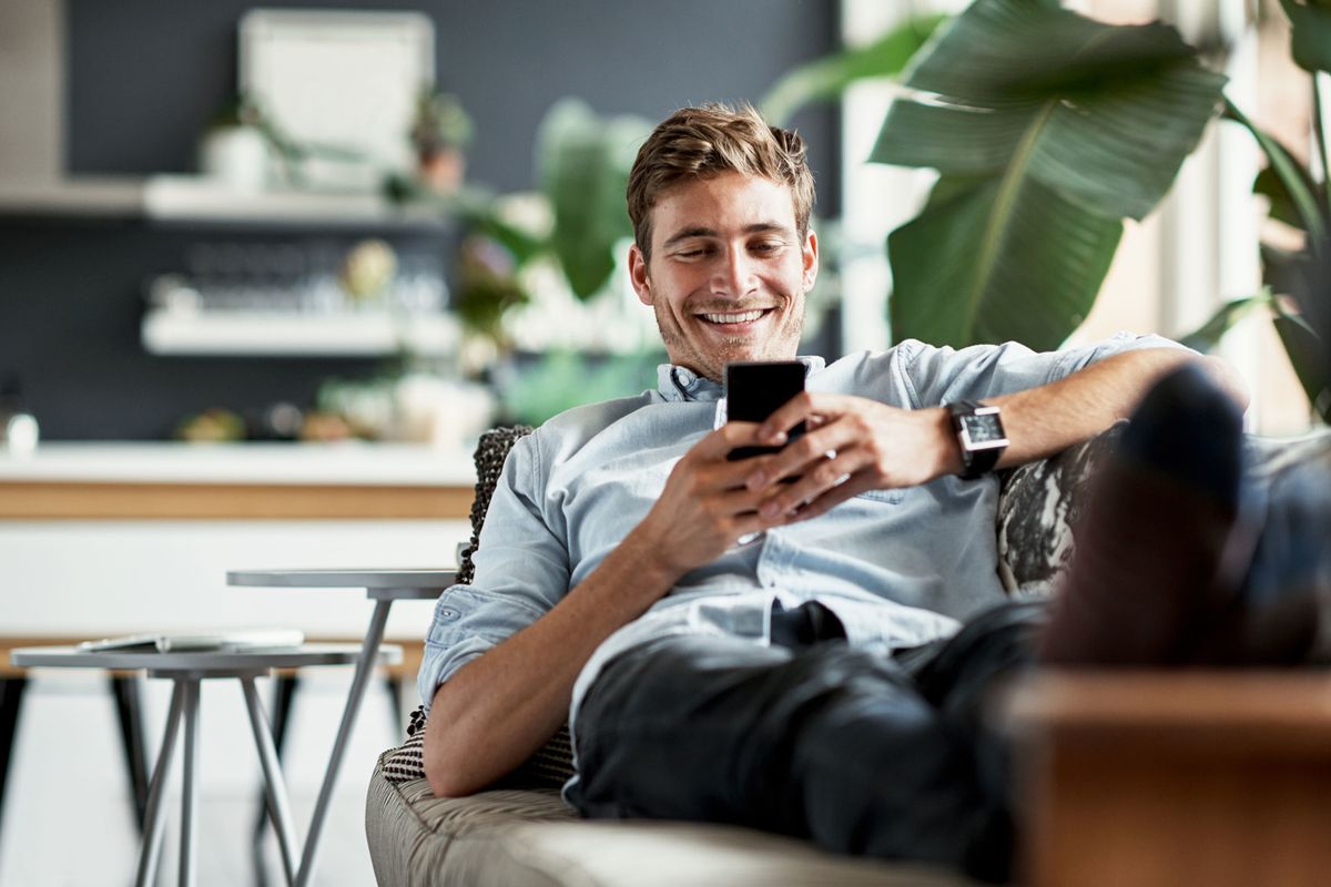 man lying on couch on his phone