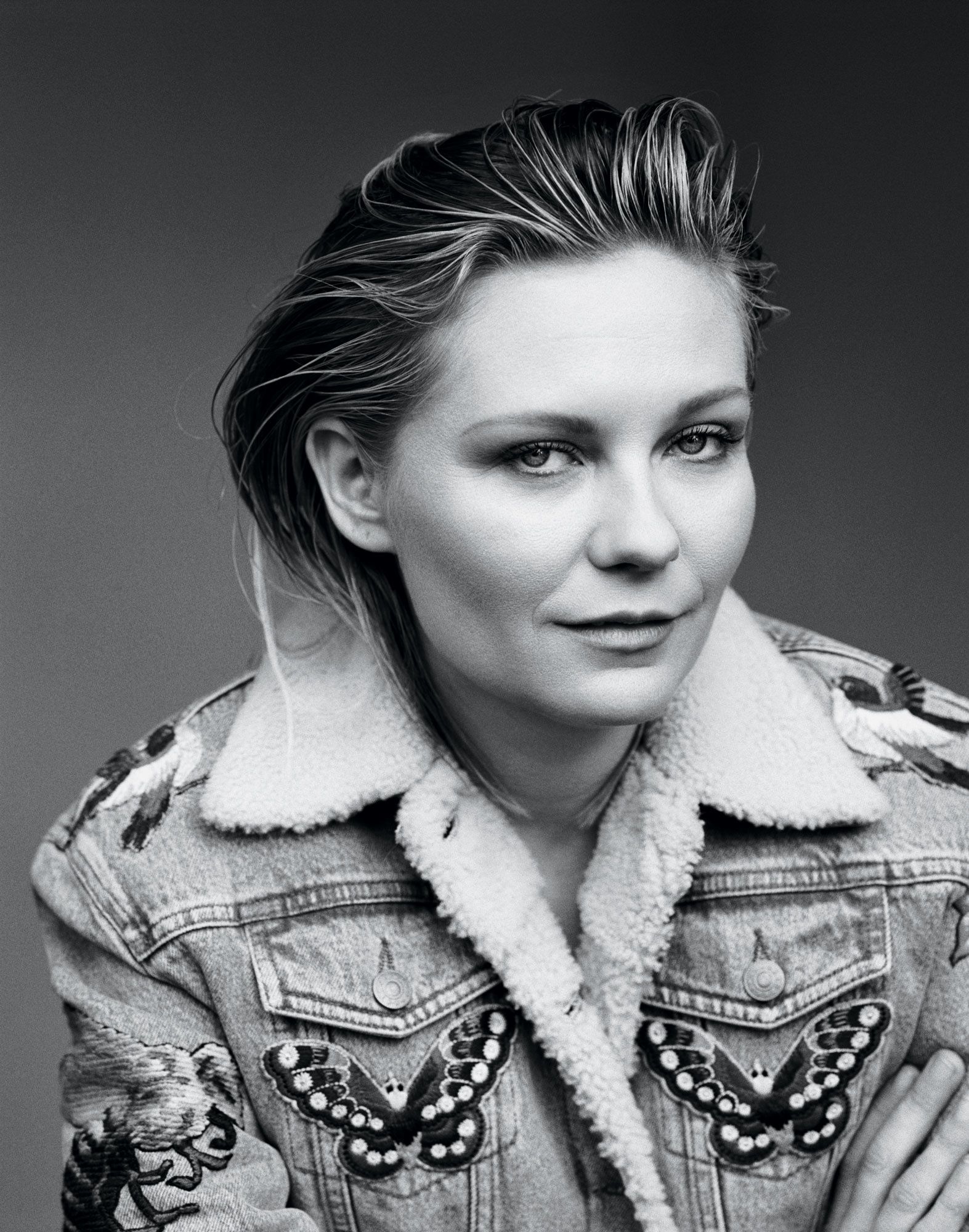 Black and white portrait of Kirsten Dunst in denim jacket.