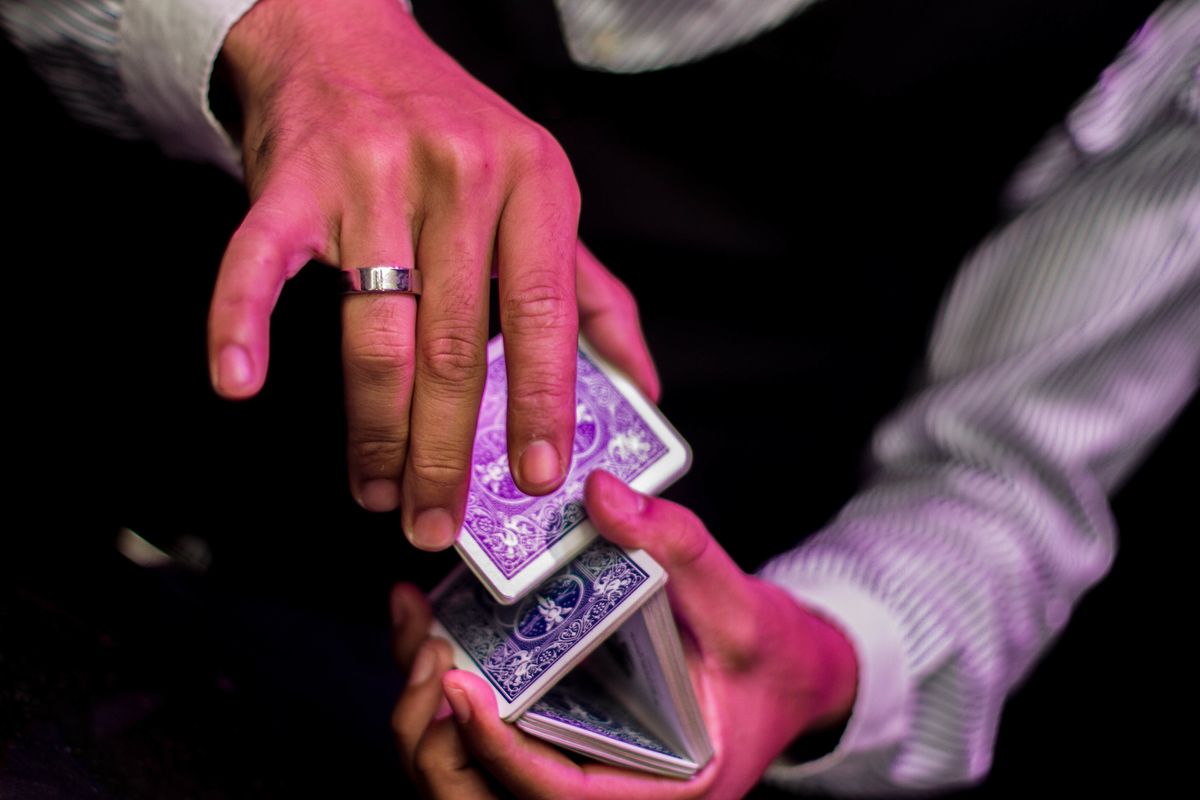 A man professionally shuffles a deck of blue playing cards at a casino table