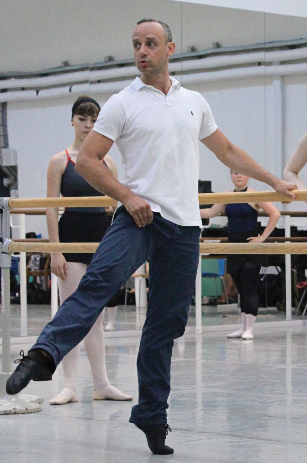 Lund stands at the barre demonstrating in navy pants and a white top