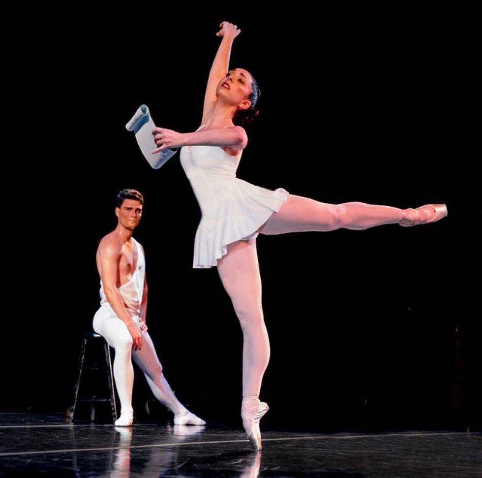 Tilton in a white dress standing in arabesque onstage holding a scroll.