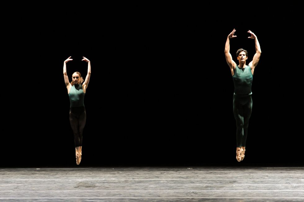 Diaz jumping in the air in sous sous in an all green unitard