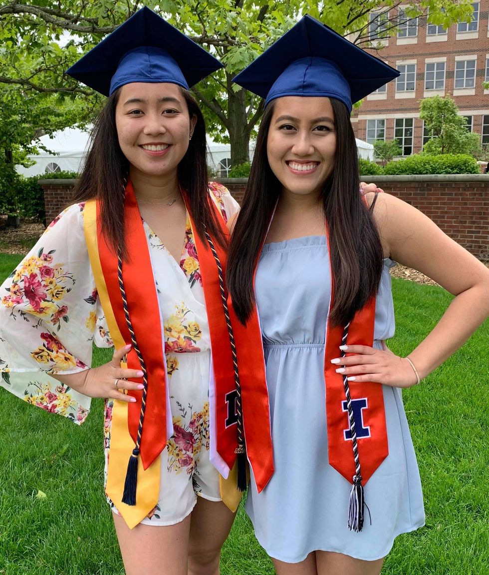Two girls wearing graduation caps, sashes, and cords. 