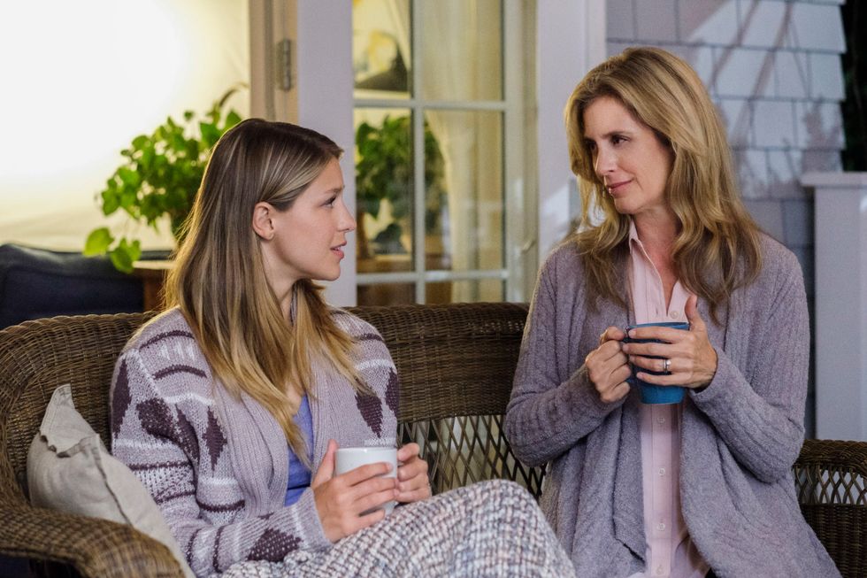Melissa Benoist as Kara sitting on a wicker couch next to her stepmom Helen Slater as Eliza Danvers
