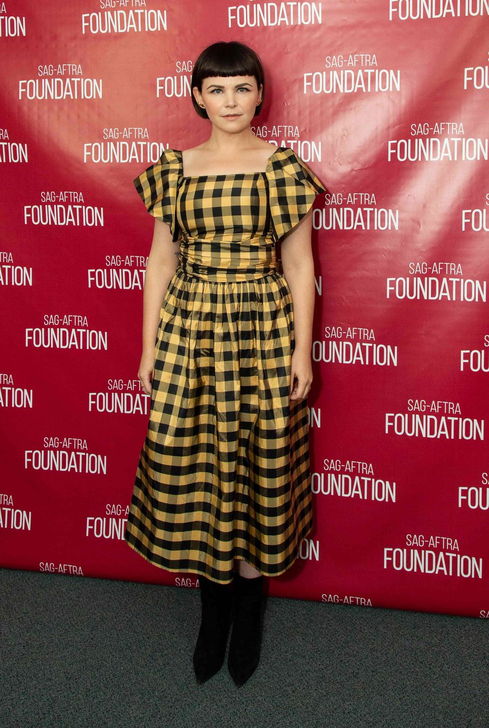 Ginnifer Goodwin in a yellow and black plaid print dress.