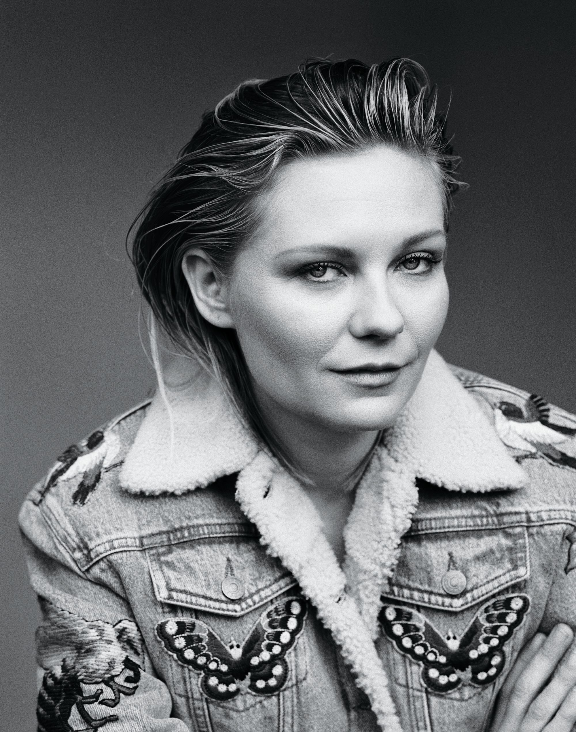Kirsten Dunst smiles enigmatically at the camera in the this black and white image.