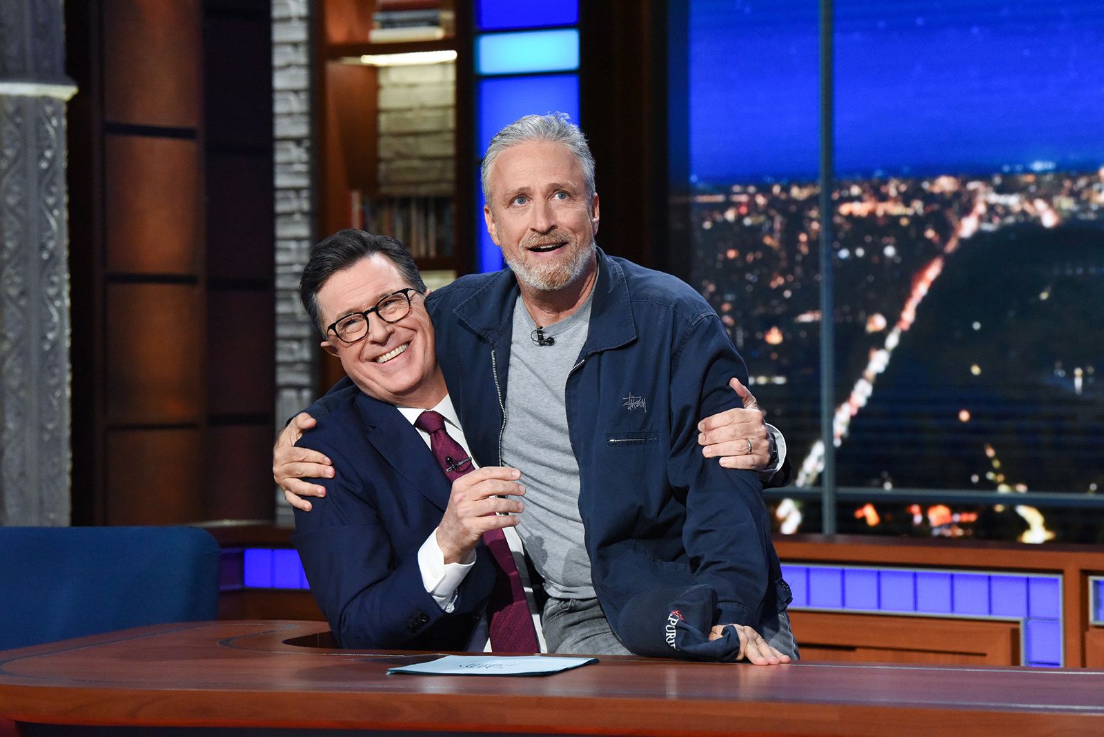Stephen Colbert with Jon Stewart sitting on his lap on the set of The Late Show With Stephen Colbert