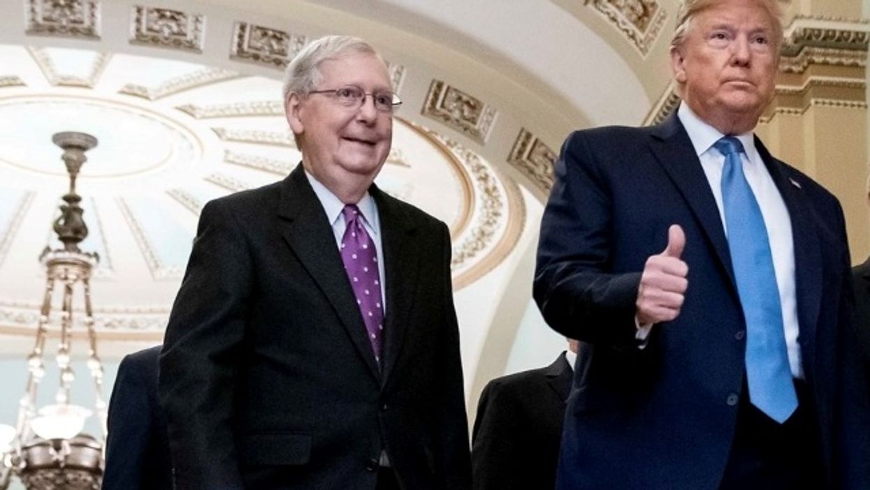 Mitch McConnell stands next to President Trump.