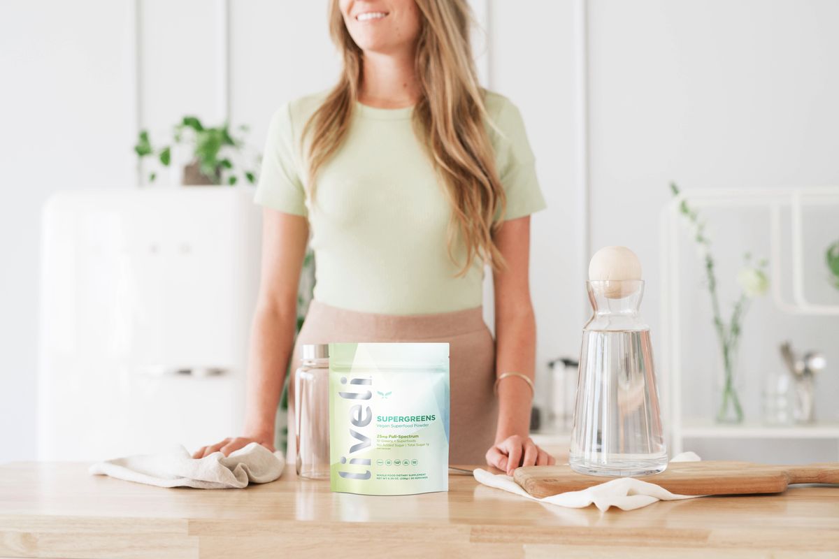 blonde woman with packet of liveli supergreens on clean kitchen counter