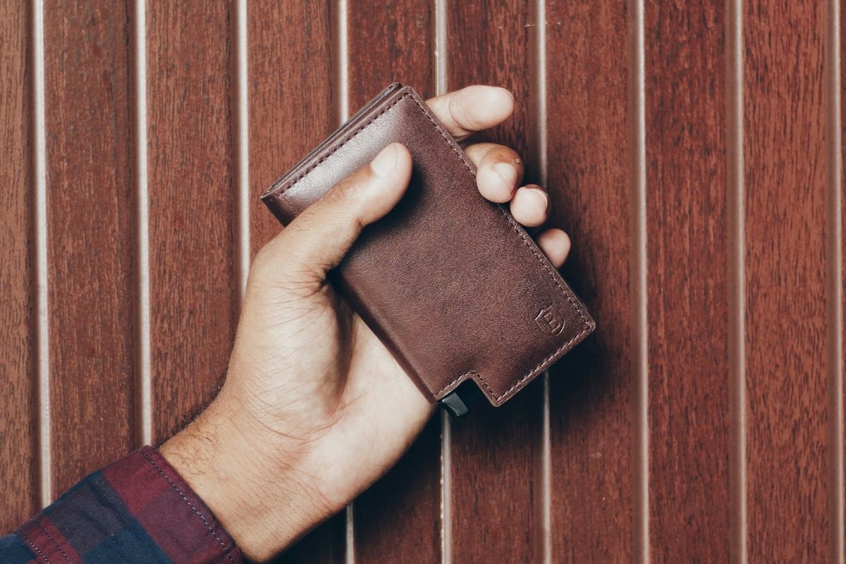 man holding brown leather Eskter wallet