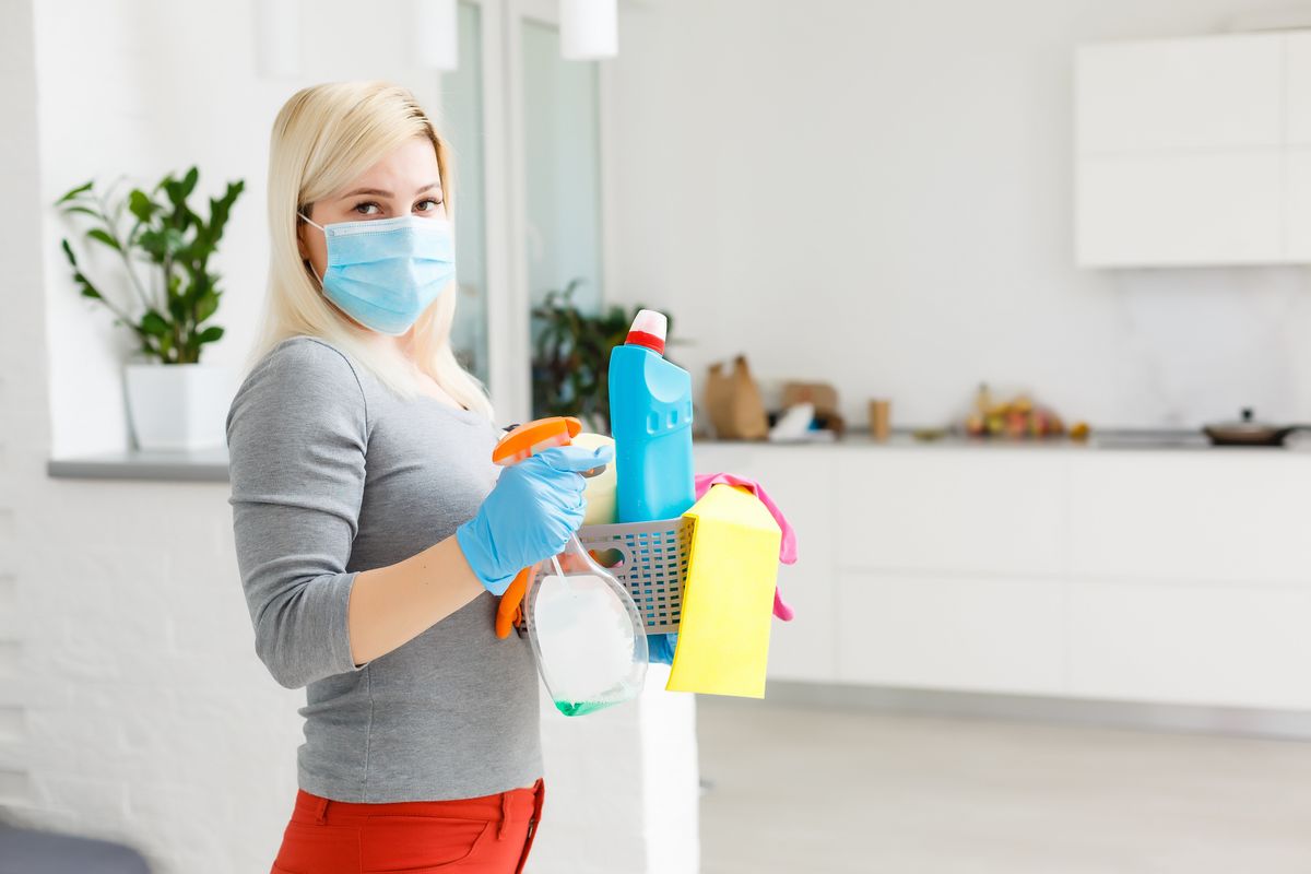 woman with cleaning supplies and a mask and gloves