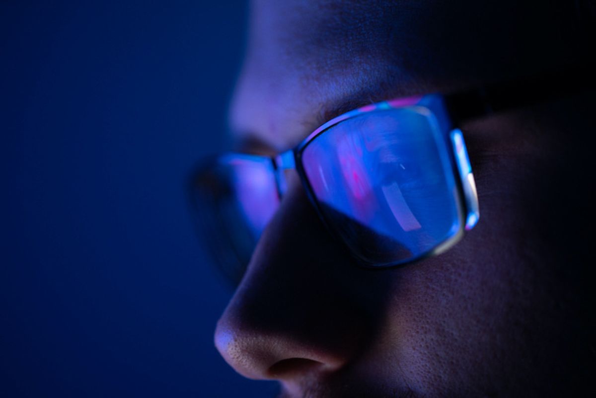 A man wearing glasses with blue light reflected