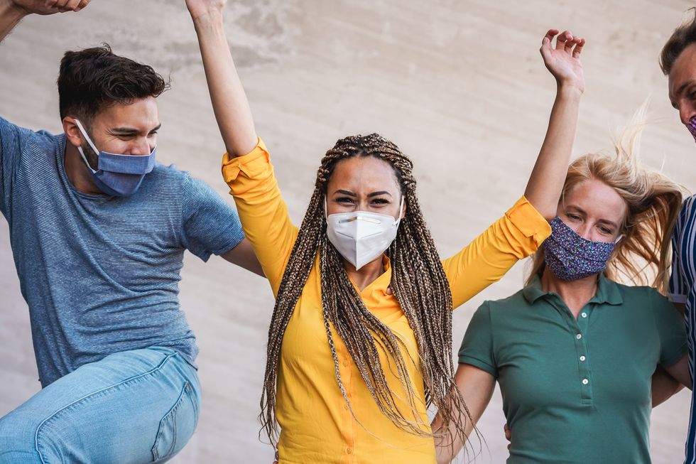 Young people having fun around city street during coronavirus outbreak - Happy friends wearing face protective masks and laughing together.