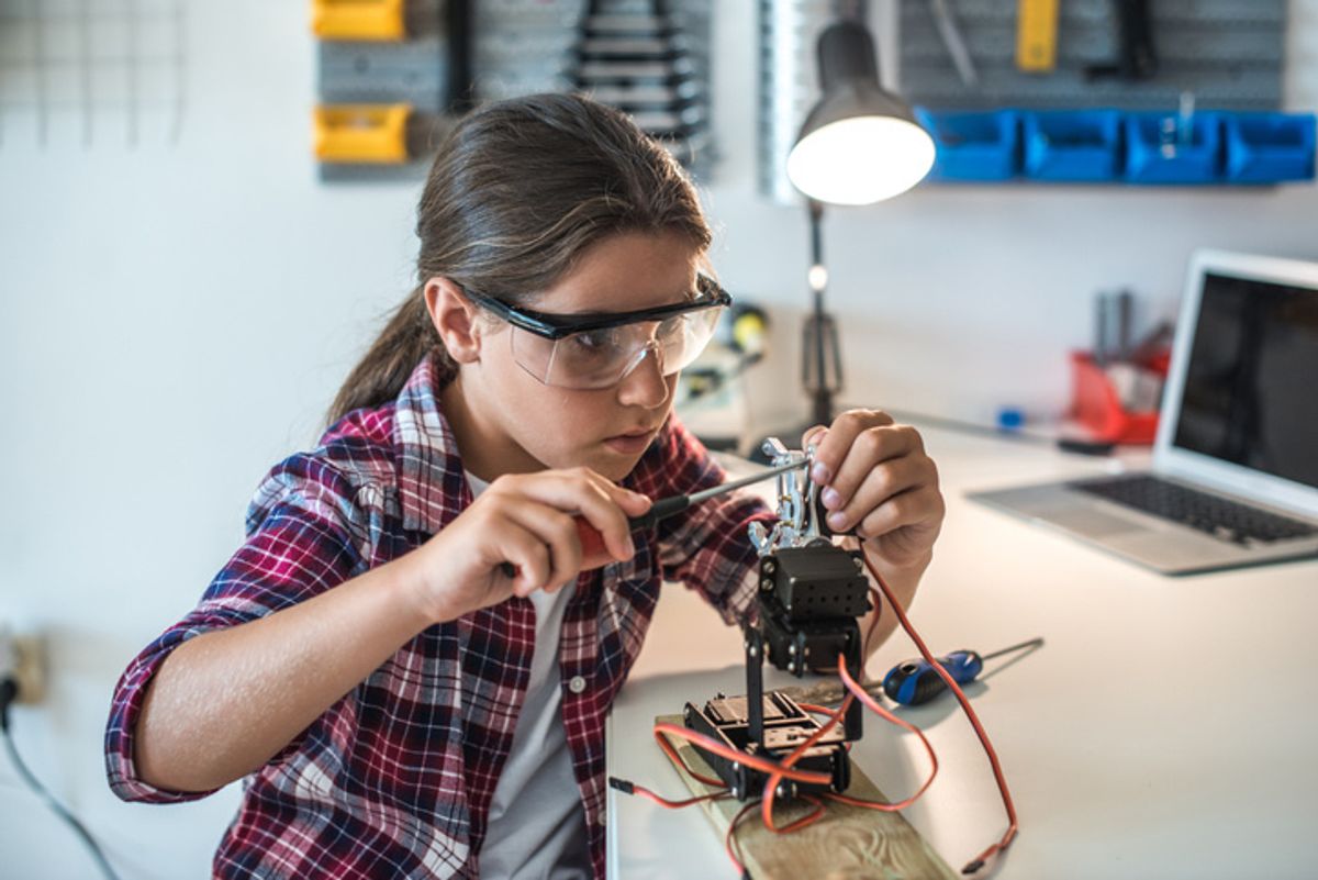 A young student building a robot on her own