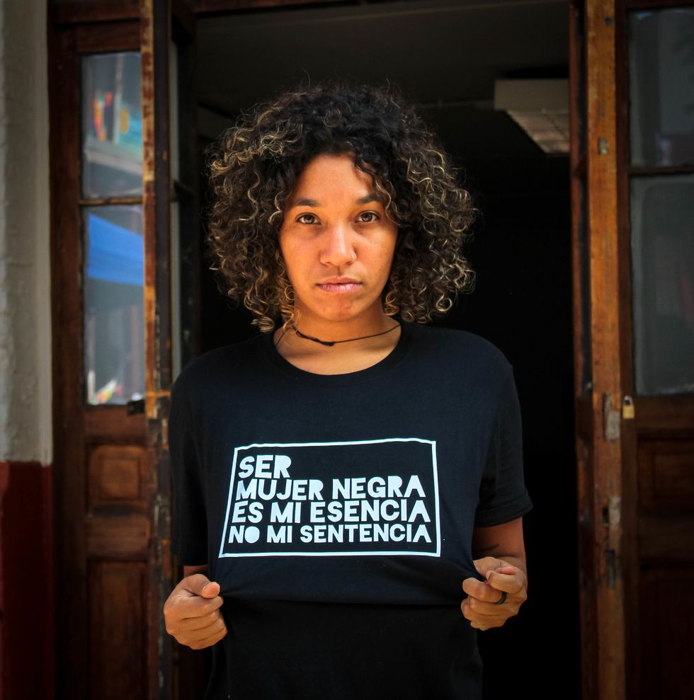 Black Chilean feminist wearing a political T-shirt that says ser mujer negra es mi esencia no mi sentencia