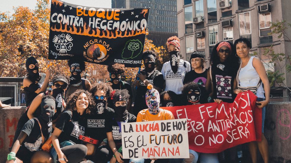 Black Chilean feminists holding signs, wearing masks, and protesting racism.