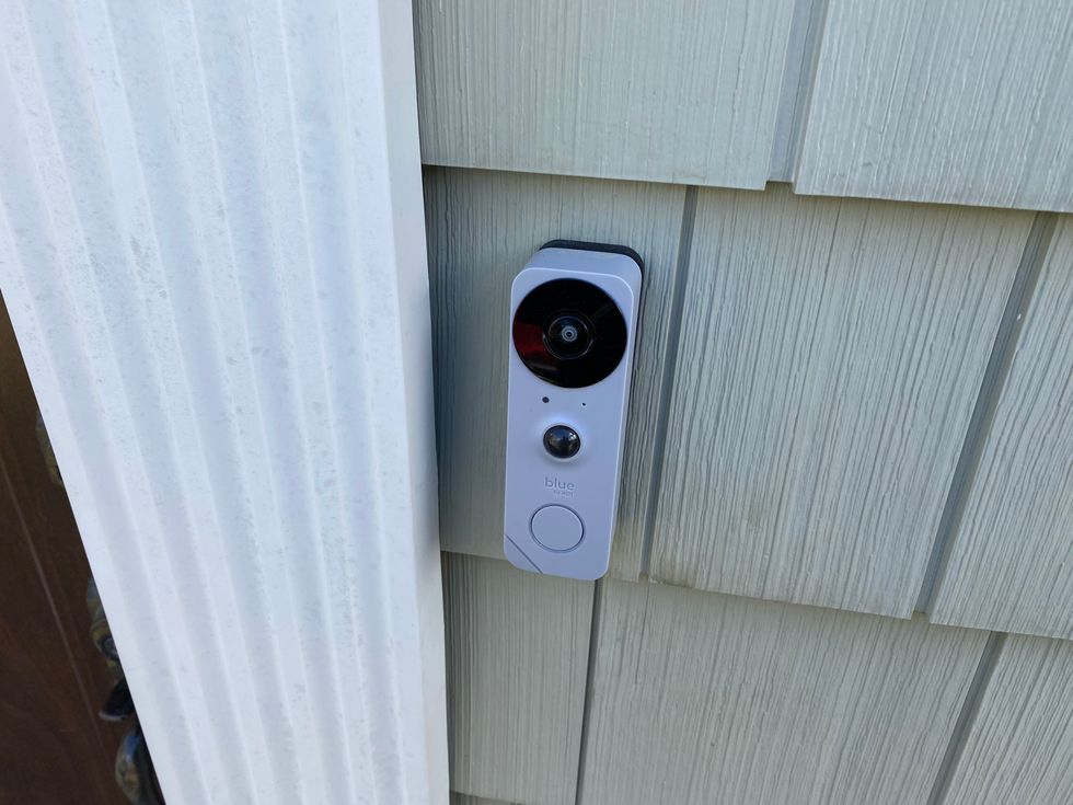 Blue Doorbell Camera installed on the side of a front entrance way of a home.