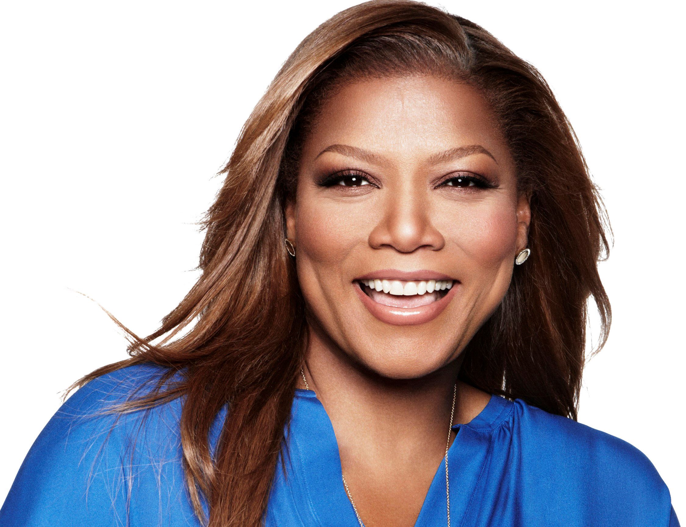 Queen Latifah smiles broadly in a glamourous and windswept look.