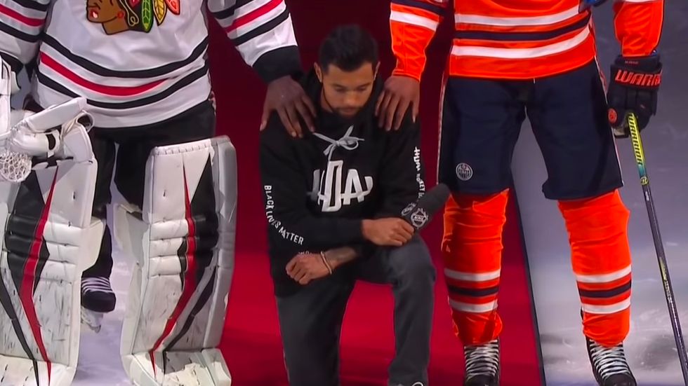 Matt Dumba kneels during the national anthem.