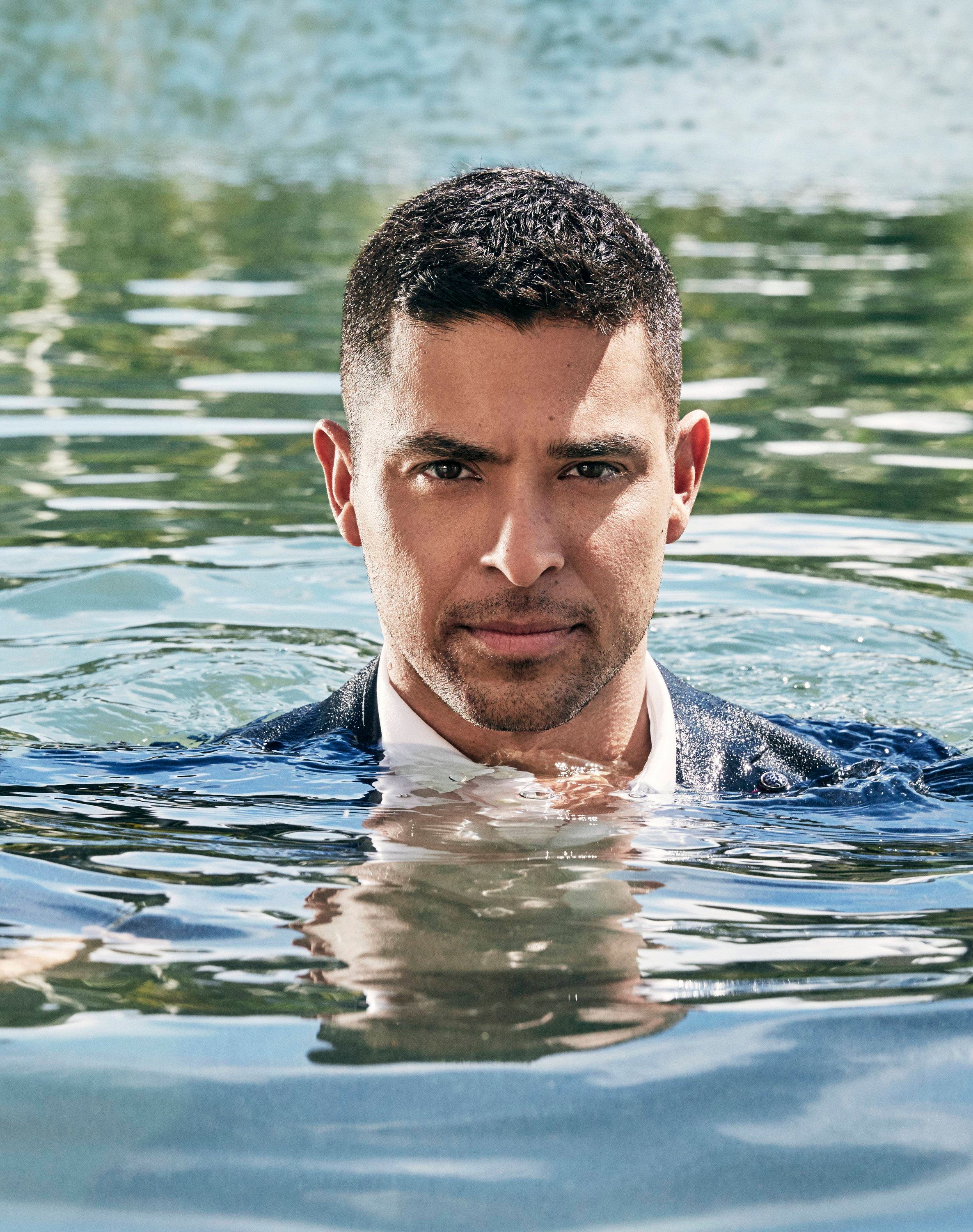 Wilmer Valderrama is fully clothed and emerging from a body of water