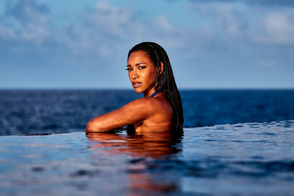 Candice Patton swims in a seaside swimming pool wearing a blue swimsuit