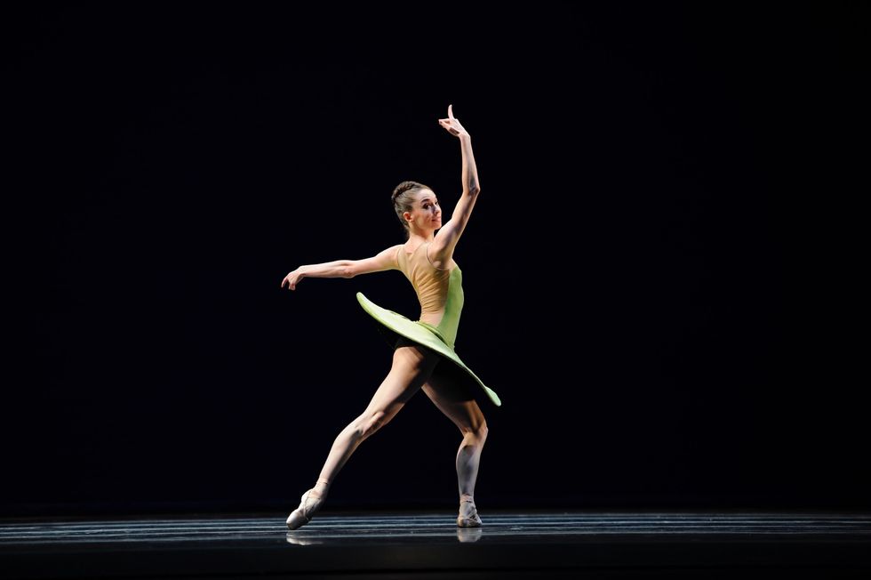 Charlene Aldred stands in profile doing tendu derrierre with her right leg back, and wears a lime green saucer tutu.