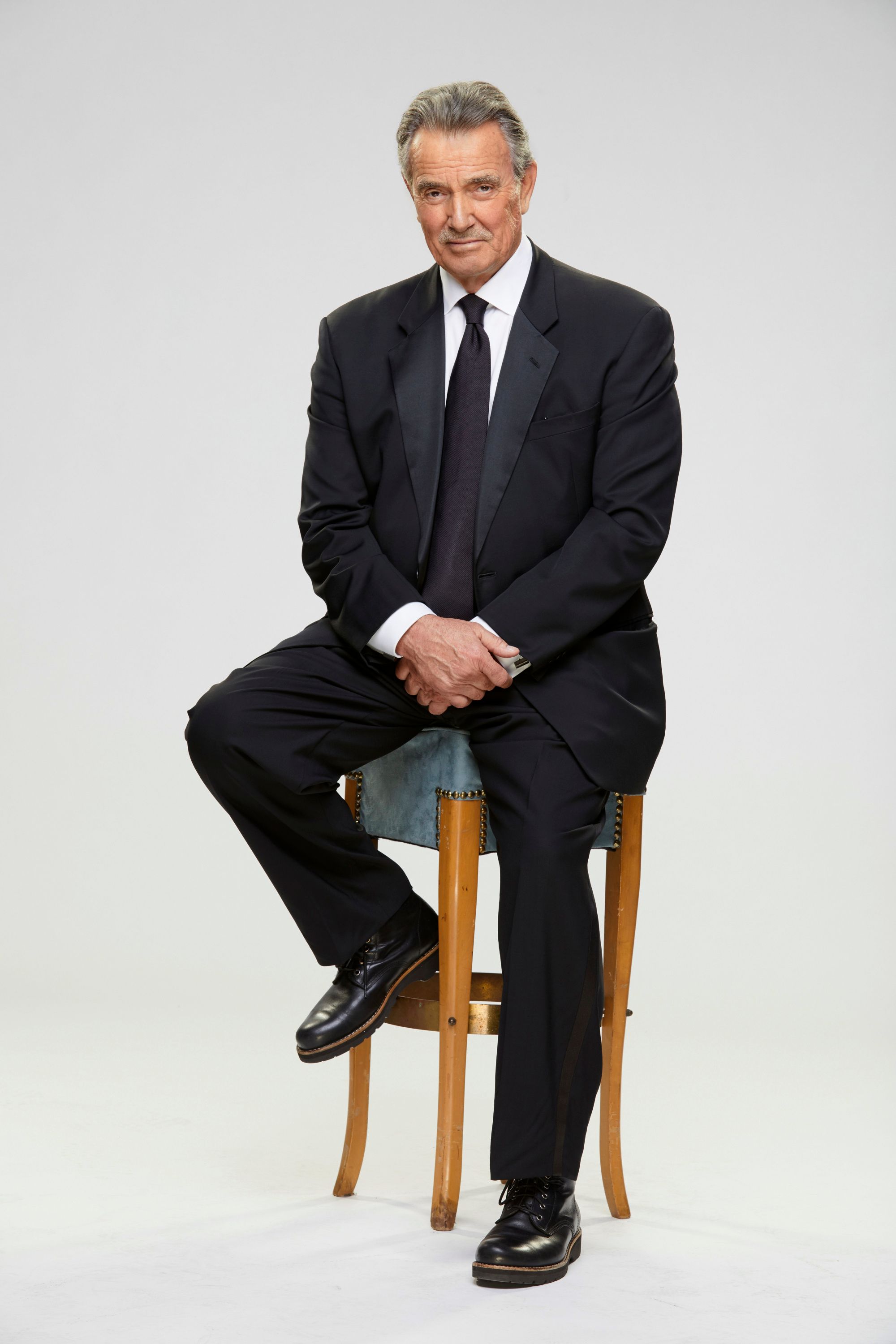 Eric Braeden as Victor Newman sitting on a stool