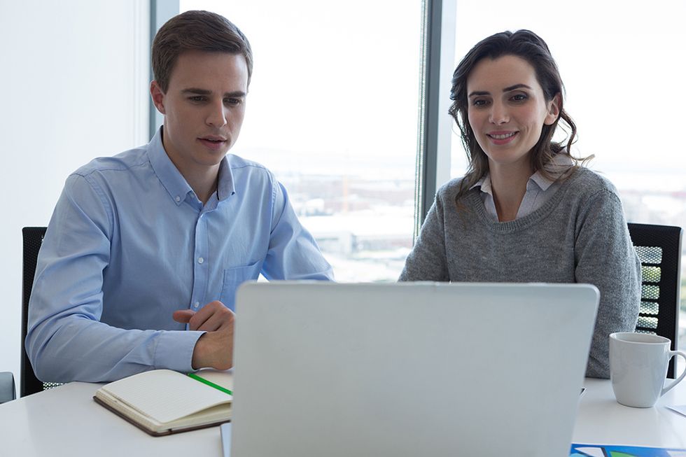 Dois colegas de trabalho colaboram juntos para resolver um problema.