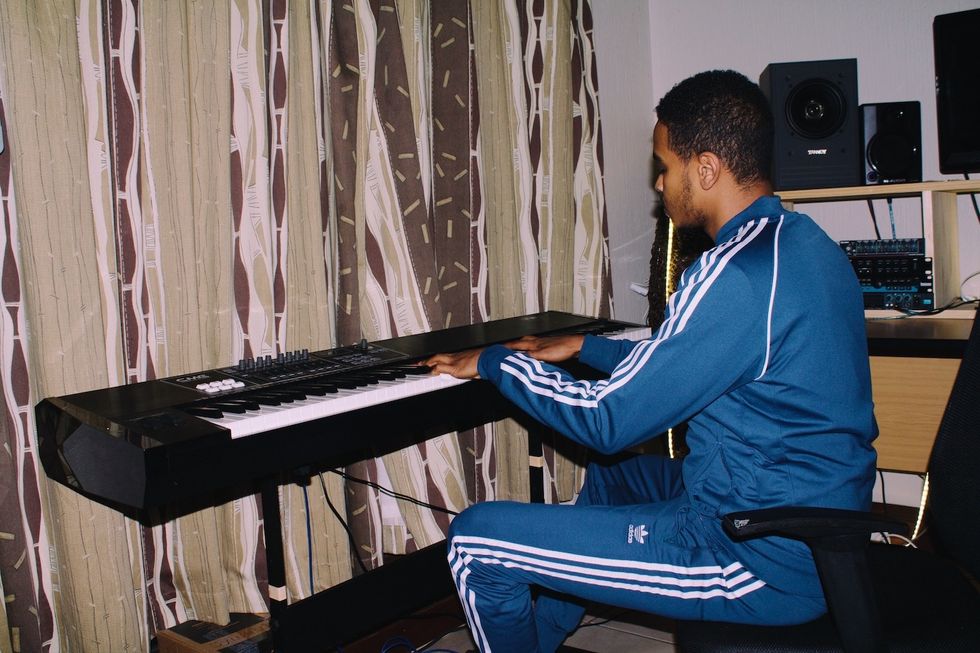 Xplosive DJ playing a keyboard in his home studio. class=