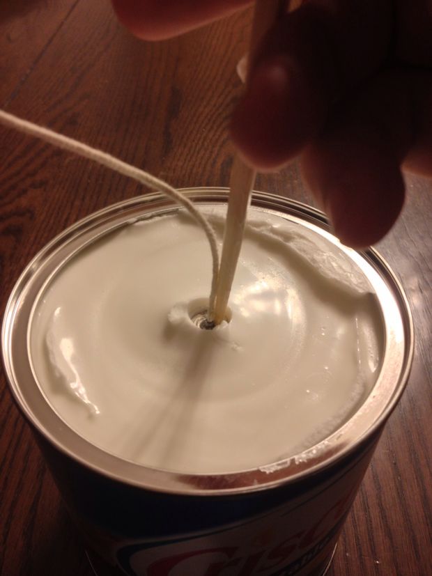 Use one hand to hold the string then use the chopstick hand to start working the wick down the hole.
