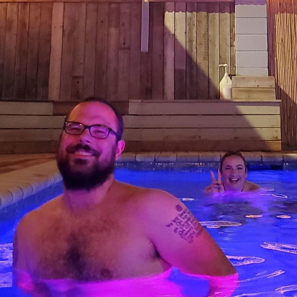 Two smiling people soaking in a pool