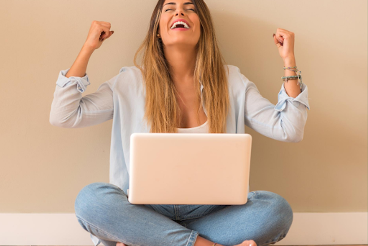 woman in jeans cheering at pink laptop