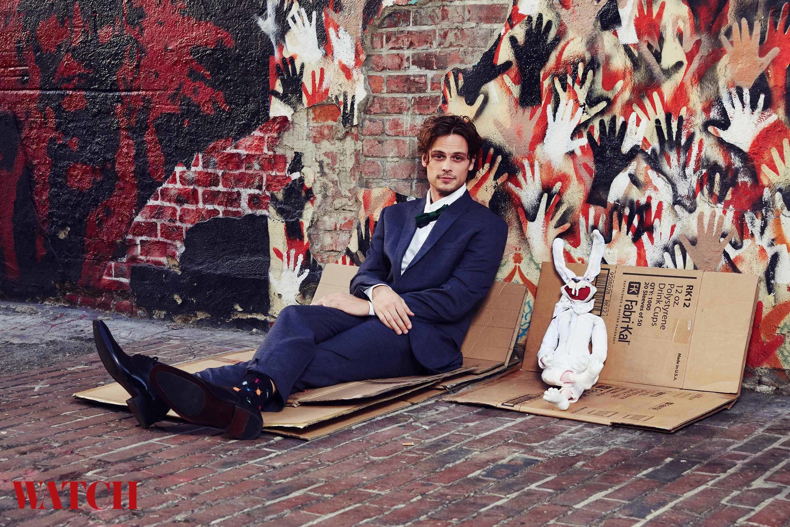 Matthew Gray Gubler sitting on a graffiti sidewalk with a stuffed bunny puppet.