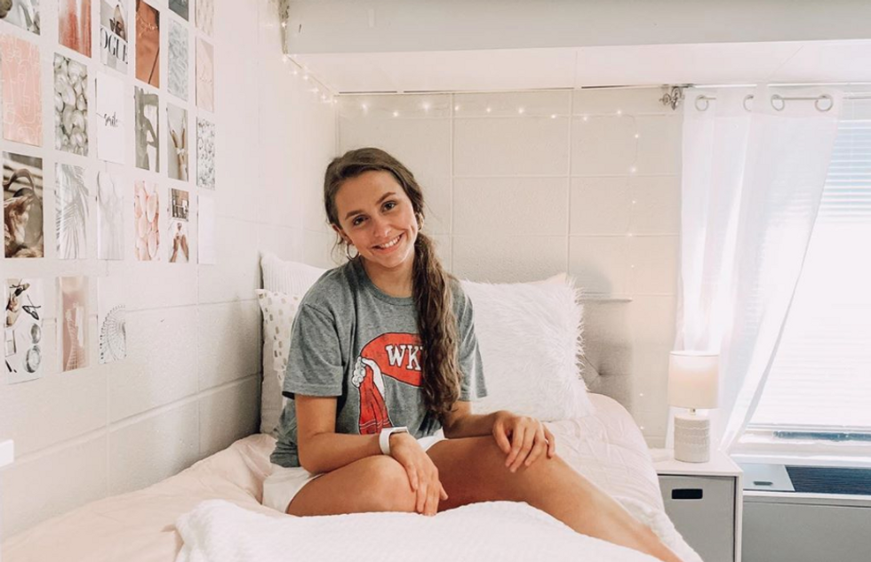 girl sitting on dorm room bed smiling